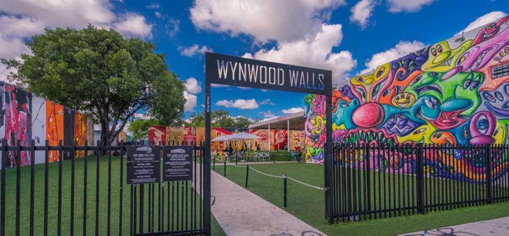 Entrance to Wynwood Walls with vibrant murals and blue sky.